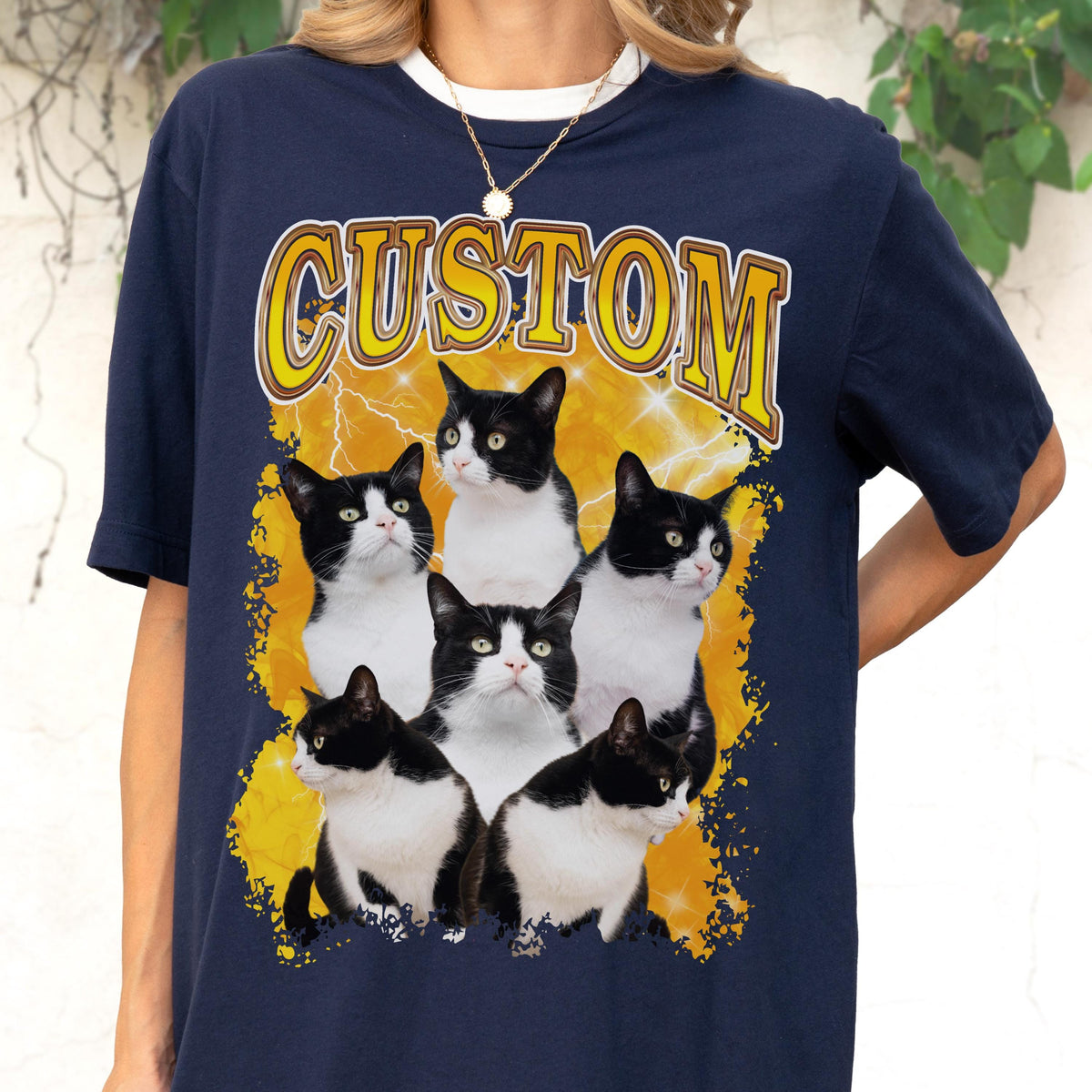 May include: Navy blue t-shirt with a white collar featuring a graphic of six black and white cats. The word "CUSTOM" is printed in yellow above the cats, set against a yellow lightning bolt design.