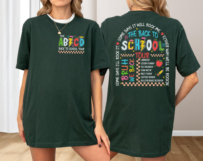 May include: Dark green t-shirt with colorful text and graphics. The front of the shirt says "THE ABCD BACK TO SCHOOL TOUR" with a lightning bolt. The back of the shirt says "THE BACK TO SCHOOL TOUR" with a list of school-related activities.
