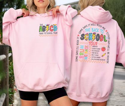 May include: A light pink hoodie with a front pocket and a hood. The front features the text "THE ABCD BACK TO SCHOOL TOUR" in colorful letters. The back of the hoodie has the text "THE BACK TO SCHOOL TOUR" with a list of school-related activities.