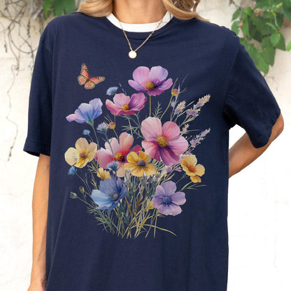May include: A navy blue short-sleeve t-shirt featuring a central graphic print of a colorful wildflower bouquet with pink, yellow, blue, and purple blossoms. A single orange and black butterfly is positioned above the flowers on the left side.