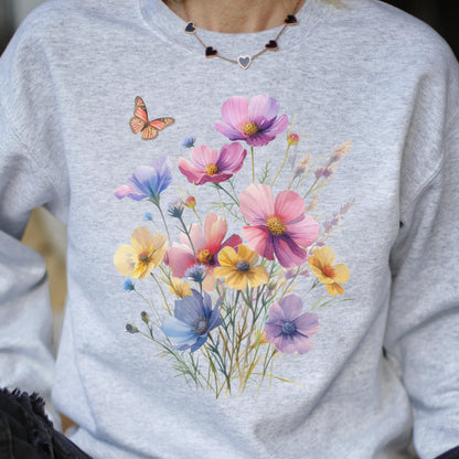May include: A light gray sweatshirt featuring a watercolor floral design with pink, yellow, and blue flowers. A small orange butterfly is on the left side of the sweatshirt. The floral design is centered on the front.