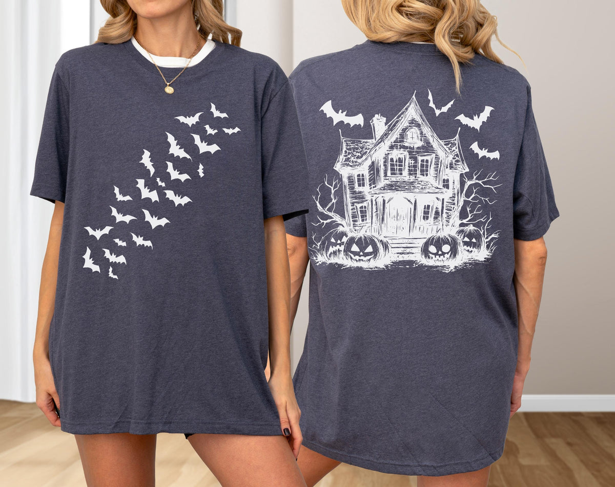 May include: Dark gray t-shirt with a white bat design on the front and a haunted house graphic on the back. The front features a diagonal pattern of bats. The back design includes a spooky house, bats, and jack-o'-lanterns.