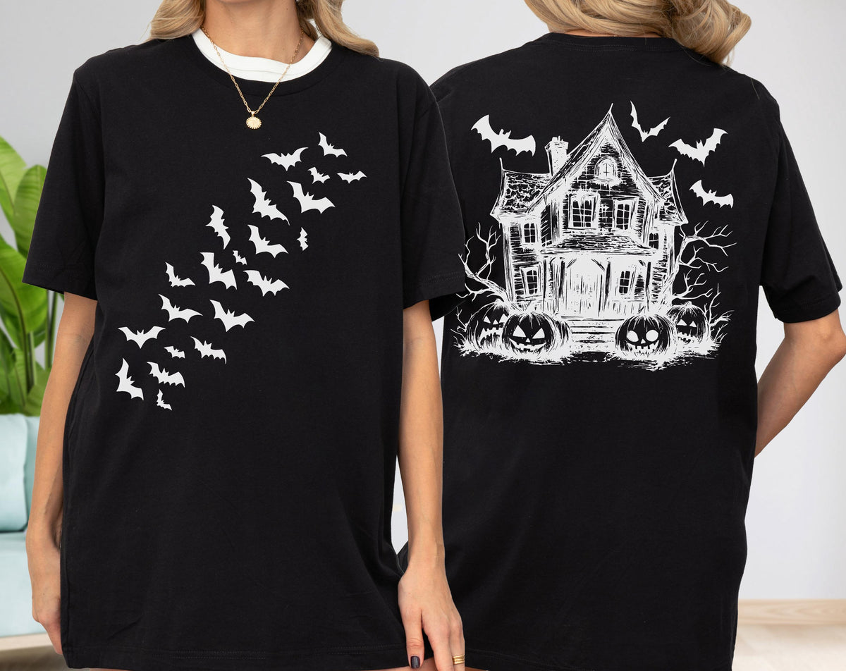 May include: Black t-shirt featuring a white bat design on the front and a haunted house with pumpkins on the back. The shirt has a crew neck and short sleeves. The design is a spooky Halloween theme.