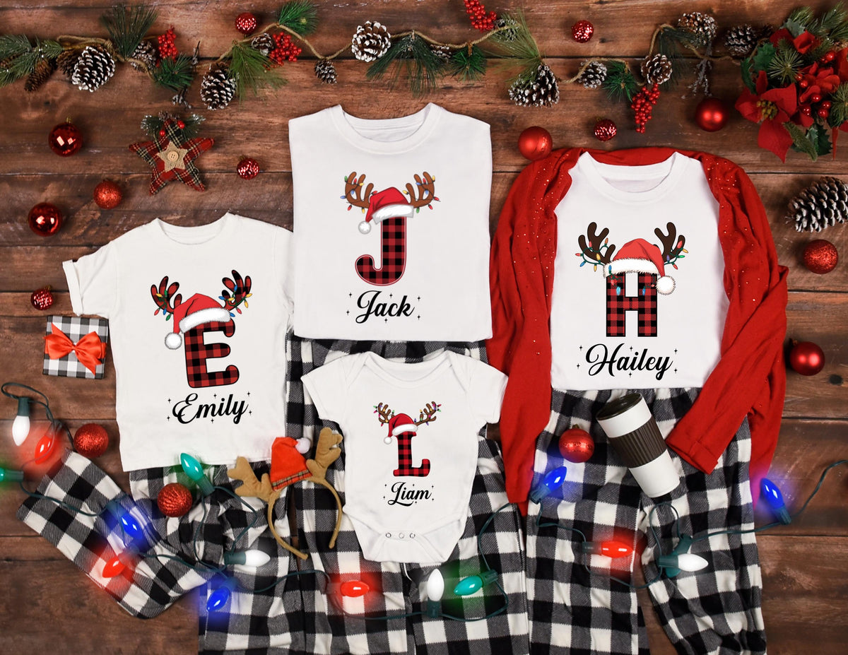 May include: A collection of white Christmas shirts and pajamas with a red and black plaid design. Each shirt features a letter, a Santa hat, and the name "Jack", "Emily", "Liam", and "Hailey". The pajamas are black and white checkered.
