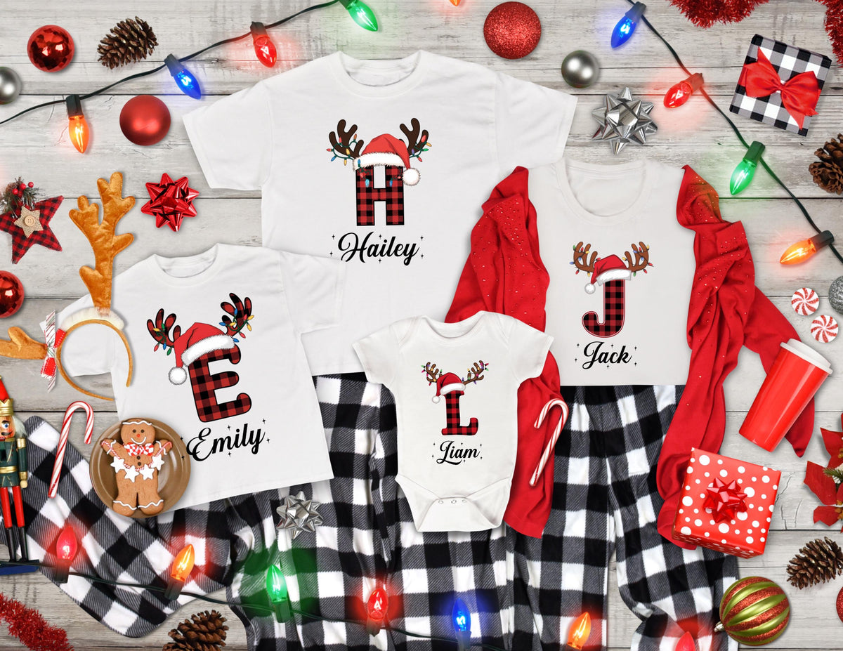 May include: White Christmas-themed family shirts and pajamas with buffalo plaid letters and reindeer antlers. The shirts are personalized with names: Hailey, Emily, Jack, and Liam. The pajamas are black and white checkered.