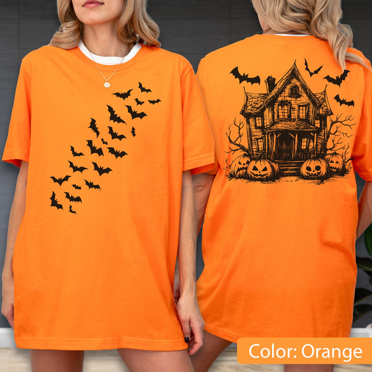 May include: An orange short-sleeve t-shirt featuring a black graphic of a swarm of bats on the front. The back of the shirt displays a black line-art illustration of a two-story house with bare trees and three jack-o'-lanterns at the base.