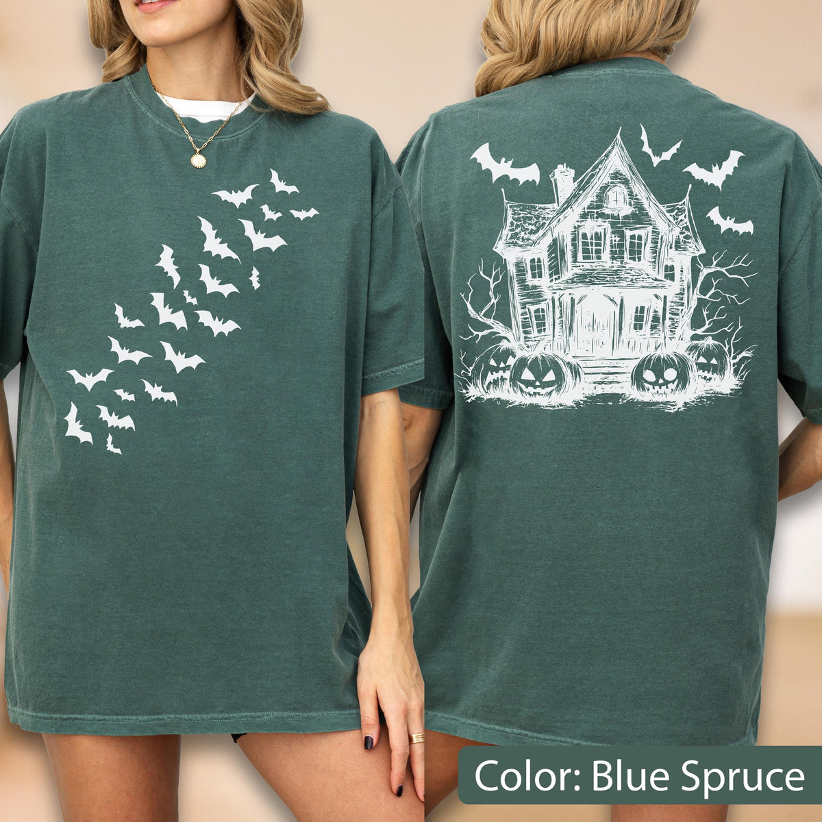 May include: A dark green t-shirt featuring a white graphic of a swarm of bats on the front. The back of the shirt displays a detailed white line drawing of a haunted house surrounded by bare trees, flying bats, and three carved jack-o'-lanterns.