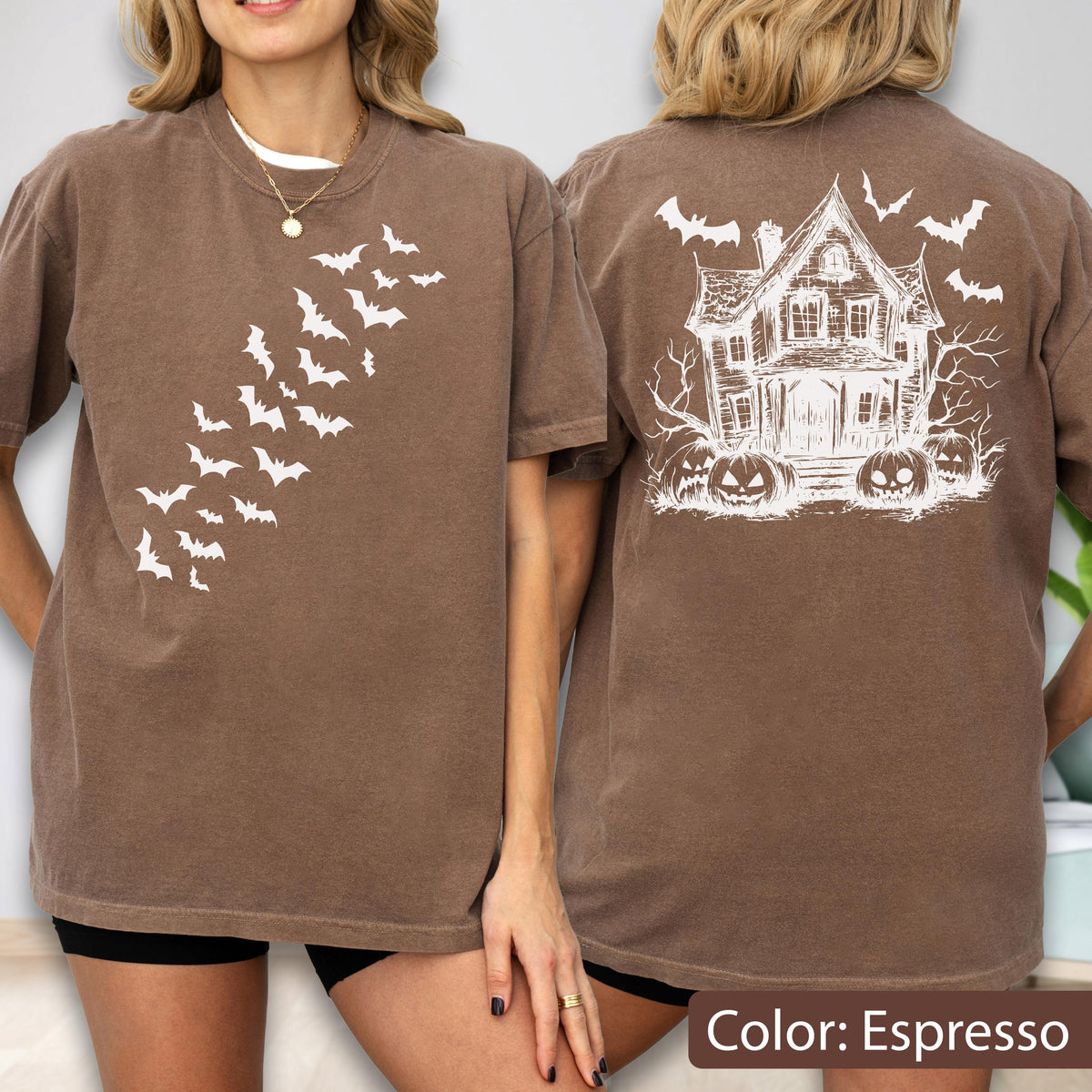 May include: A brown short-sleeve t-shirt featuring a white graphic of a diagonal swarm of bats on the front chest. The back of the shirt displays a white line-art illustration of a haunted house surrounded by pumpkins and flying bats.