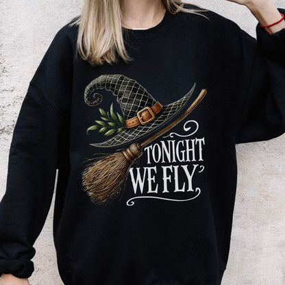 May include: A black long-sleeve sweatshirt featuring a graphic print of a black witch hat with a brown buckle and green leaves, a wooden broomstick, and the white text "TONIGHT WE FLY" written in a decorative script font on the front.