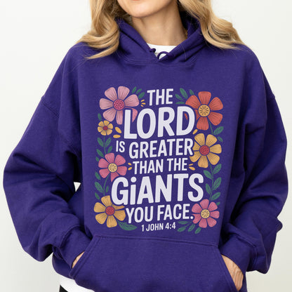 May include: A purple hoodie with a floral design and the text "THE LORD IS GREATER THAN THE GIANTS YOU FACE. 1 JOHN 4:4". The design features colorful flowers in pink, orange, and yellow.