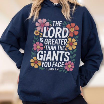 May include: Navy blue hoodie with a floral design and the text "THE LORD IS GREATER THAN THE GIANTS YOU FACE. 1 JOHN 4:4". The design features pink, yellow, and orange flowers with green leaves.