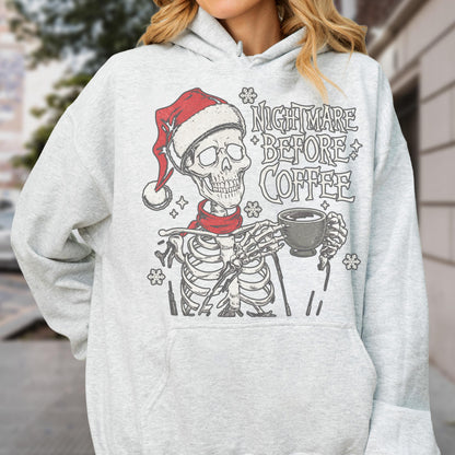 May include: Light gray hoodie featuring a skeleton wearing a Santa hat and red scarf, holding a coffee cup. The text "NIGHTMARE BEFORE COFFEE" is printed above the skeleton. The design includes snowflakes.