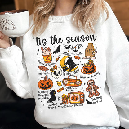 May include: White sweatshirt with a colorful Halloween-themed graphic. The design includes pumpkins, bats, a witch, and the text "'tis the season." Other elements include a skull, a black cat, and the words "Pumpkin Spices" and "Trick or Treating."