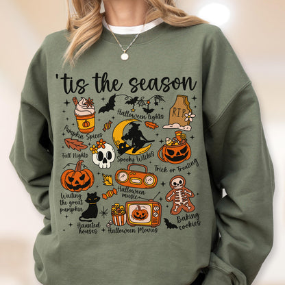 May include: Sage green sweatshirt with a Halloween-themed graphic. The design includes various icons such as pumpkins, bats, a skull, and the text "'tis the season". The sweatshirt is a comfortable, casual garment.
