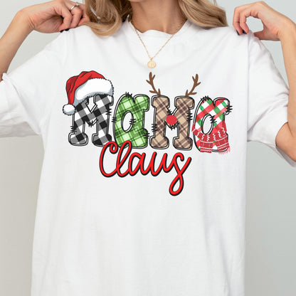 May include: White t-shirt featuring the text "Mama Claus" in a festive design. The letters are decorated with a Santa hat, plaid patterns, antlers, and a scarf, all in Christmas colors. The word "Claus" is in a red script font.