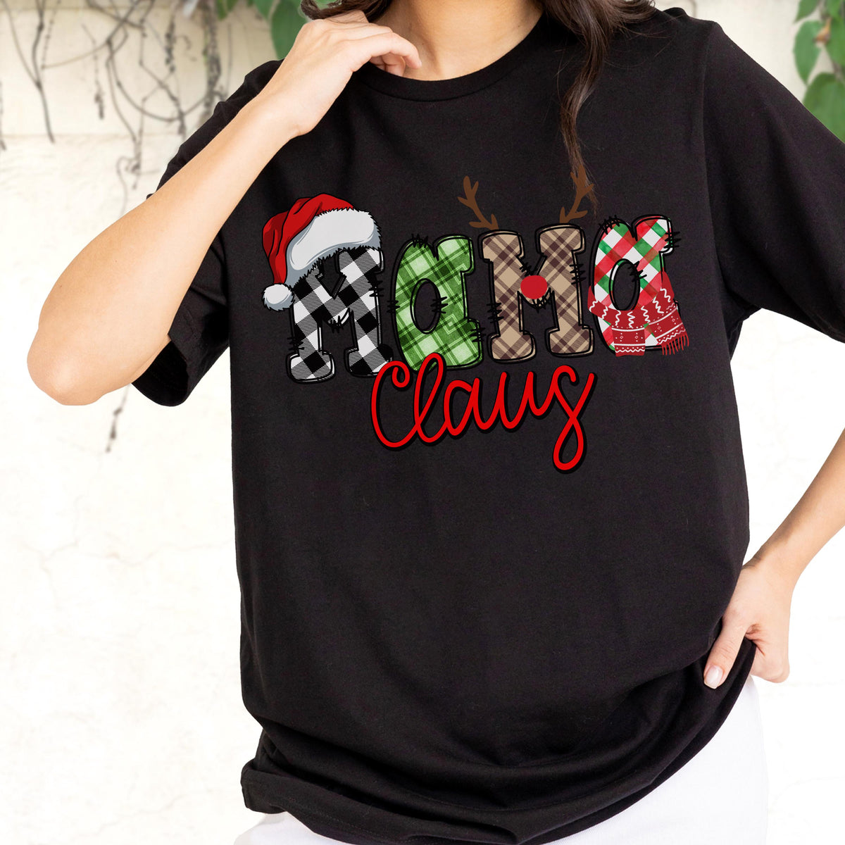 May include: Black t-shirt with the text "Ho Ho Claus" in a festive design. The letters are decorated with a Santa hat, plaid patterns, and a scarf, perfect for the holiday season.