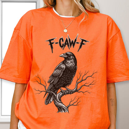 May include: Bright orange t-shirt featuring a detailed black raven perched on a tree branch. The text "F-CAW-F" is above the raven. The shirt has short sleeves and a round neckline.