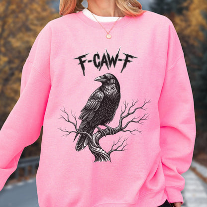 May include: A bright pink long-sleeve sweatshirt featuring a black graphic illustration of a raven perched on a bare tree branch. Above the bird, the text F-CAW-F is printed in a jagged, distressed black font. The garment has a crew neckline.