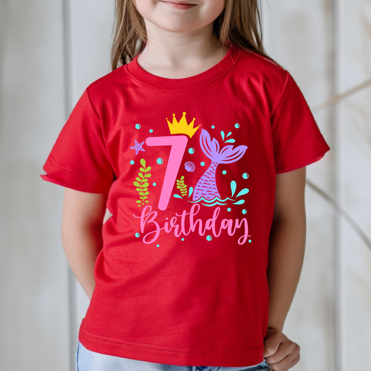 May include: Red t-shirt with a colorful mermaid-themed design for a 7th birthday. The graphic includes a crown, a mermaid tail, the number 7, and the word "Birthday".