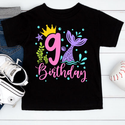 May include: Black t-shirt with a colorful mermaid-themed design for a 9th birthday. The design includes a pink number 9, a mermaid tail, a crown, and the word "Birthday" in pink script.