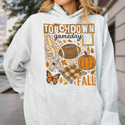 May include: A light gray hoodie with a graphic design featuring the words "TOUCHDOWN gameday FALL". The design includes a football, pumpkin, foam finger, butterfly, and a blanket.