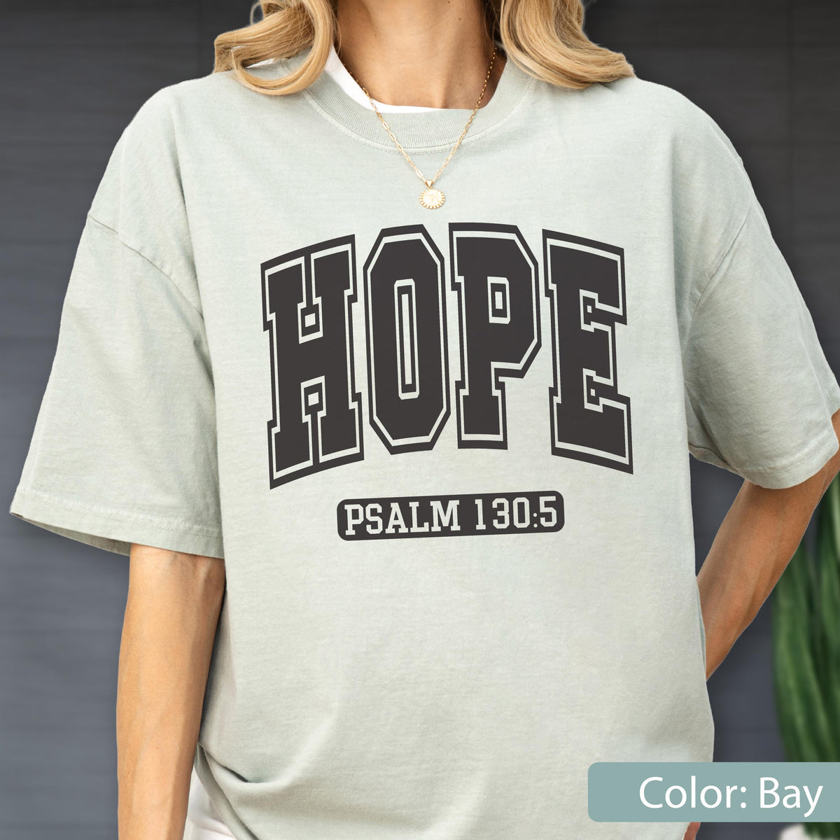 May include: A light sage green short-sleeve t-shirt featuring the word HOPE in large black collegiate-style block lettering across the chest, with the text PSALM 130:5 printed in a smaller black rectangular box directly underneath the main word.