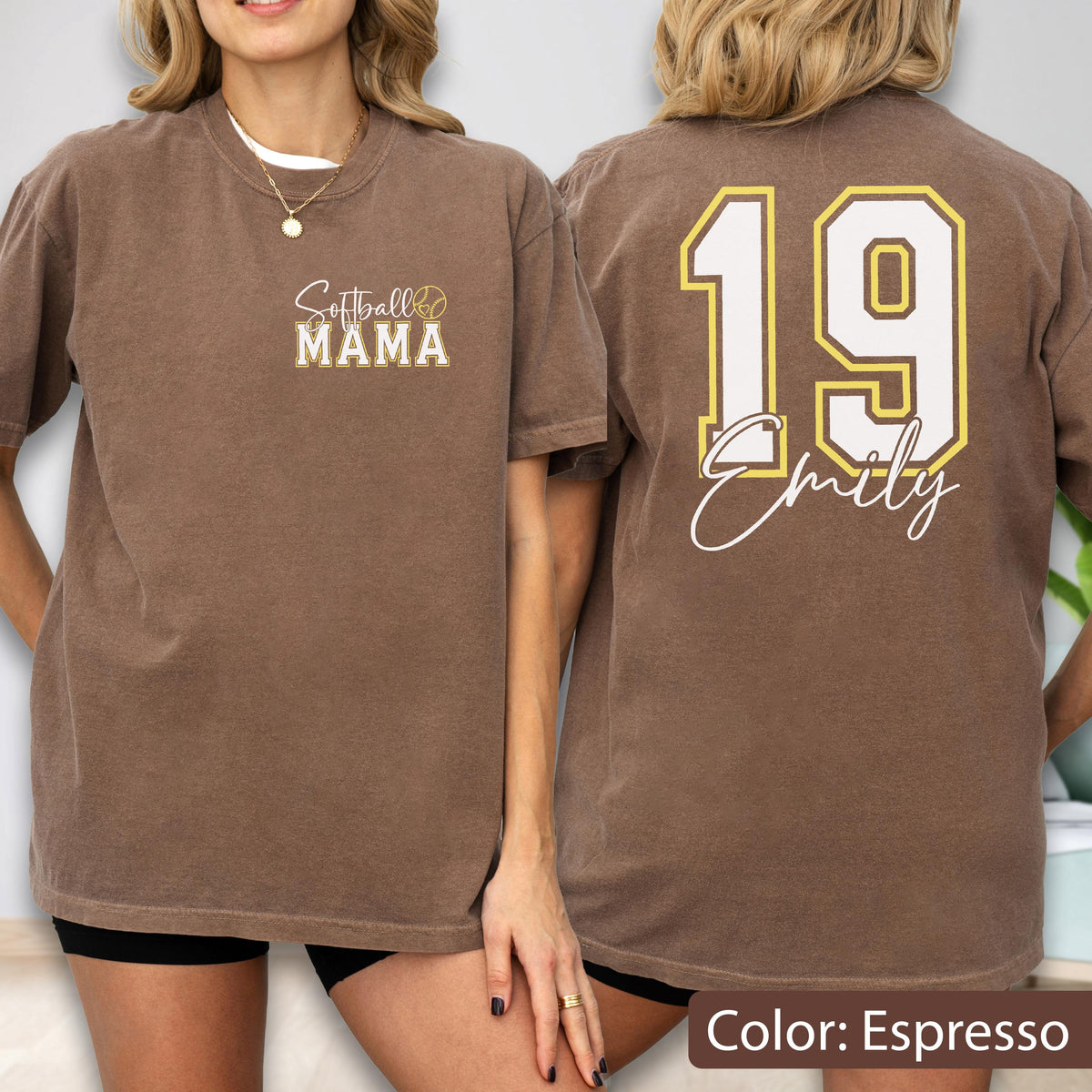 May include: Espresso-colored t-shirt with "Softball Mama" text on the front and "19 Emily" on the back. The text is in white and gold. The shirt is a casual, short-sleeved style.
