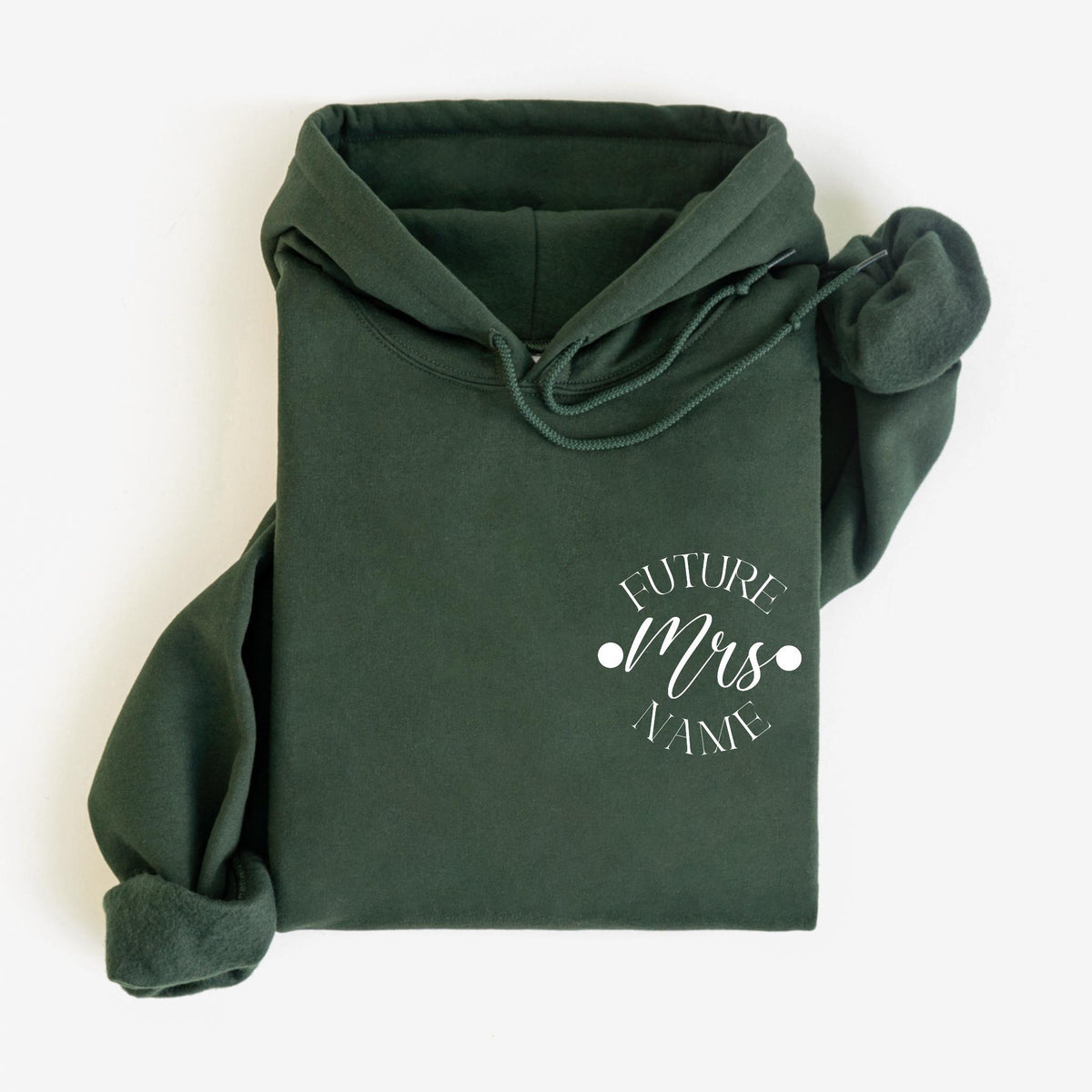 May include: Dark green hoodie with a drawstring hood and a front pocket. The hoodie features the text "FUTURE Mrs NAME" in white, within a circular design. The sleeves are folded, and the garment is laid flat.