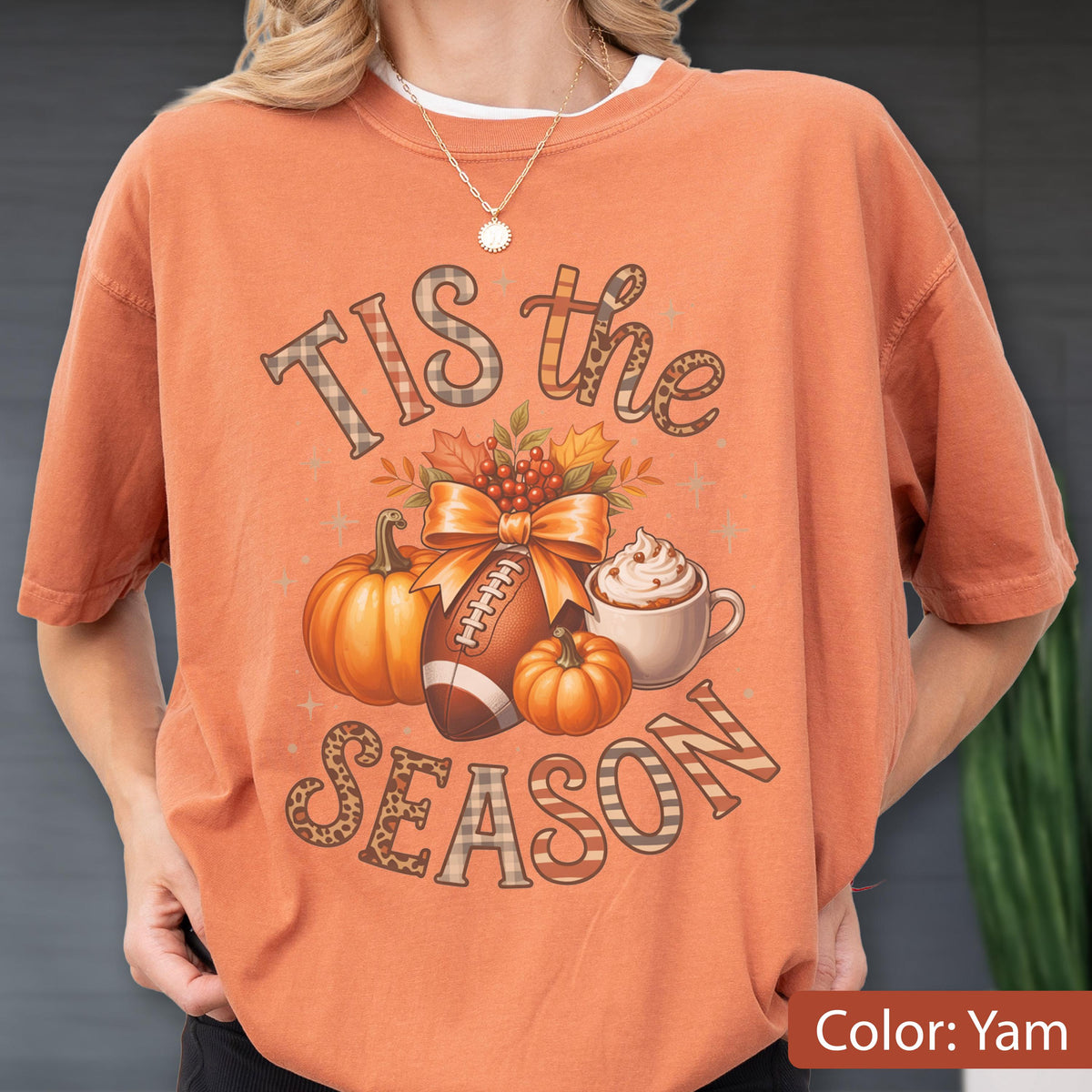 May include: Orange short-sleeved t-shirt with the text "Tis the Season" in a decorative font. The graphic includes a football, pumpkins, a bow, and a cup of whipped cream. The shirt is a yam color.