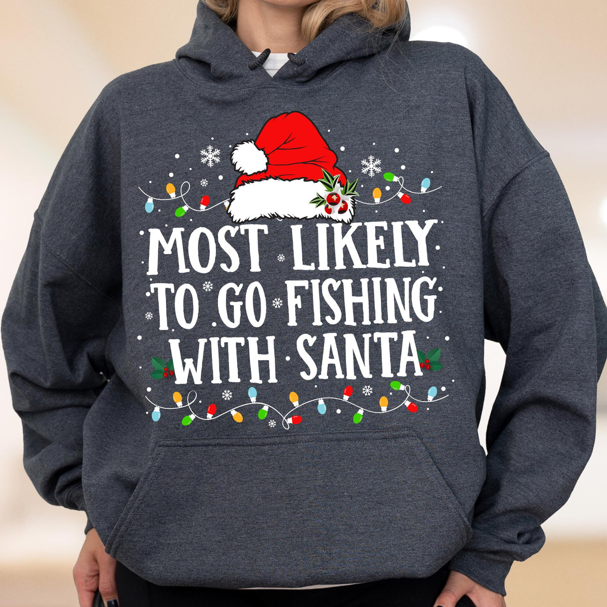 May include: A dark charcoal gray hooded sweatshirt featuring a graphic print of a red Santa hat with holly, white snowflakes, and colorful Christmas lights. The text reads, "MOST LIKELY TO GO FISHING WITH SANTA" in bold white capital letters.