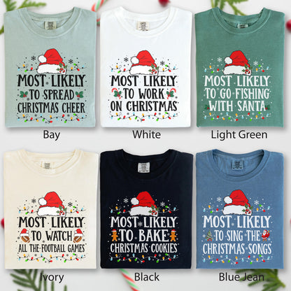 May include: Six different colored t-shirts with Christmas-themed text and graphics. Each shirt features a Santa hat, string lights, and text like "Most Likely to Spread Christmas Cheer." Colors include bay, white, light green, ivory, black, and blue jean.