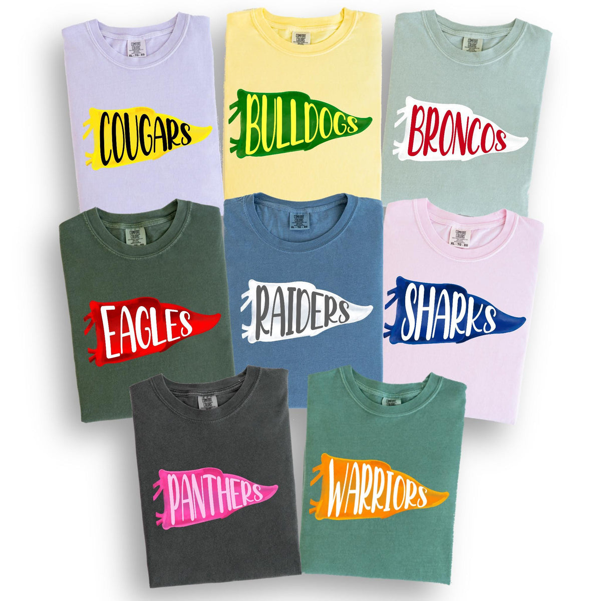 May include: A collection of crew neck t-shirts in various colors, each featuring a team name in a pennant design. Colors include light purple, yellow, green, blue, pink, and gray. The team names are Cougars, Bulldogs, Broncos, Eagles, Raiders, Sharks, Panthers, and Warriors.