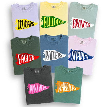 May include: A collection of crew neck t-shirts in various colors, each featuring a team name in a pennant design. Colors include light purple, yellow, green, blue, pink, and gray. The team names are Cougars, Bulldogs, Broncos, Eagles, Raiders, Sharks, Panthers, and Warriors.