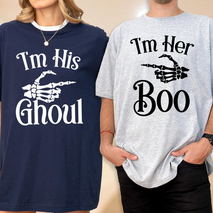 May include: A navy blue t-shirt with white text reading I'm His Ghoul and a skeleton hand graphic, alongside a light gray t-shirt with black text reading I'm Her Boo and a skeleton hand graphic pointing toward the navy blue t-shirt.