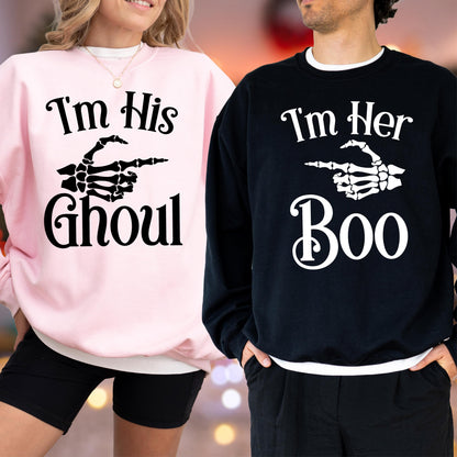 May include: Matching Halloween sweatshirts. One is light pink with the text "I'm His Ghoul" and a skeleton hand pointing to the right. The other is black with "I'm Her Boo" and a skeleton hand pointing to the left. Both have white trim.
