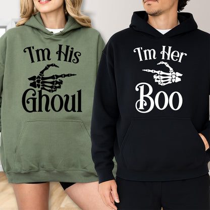 May include: Two hooded sweatshirts, one olive green and one black. The olive green sweatshirt has the text "I'm His Ghoul" with a skeleton hand pointing to the right. The black sweatshirt says "I'm Her Boo" with a skeleton hand pointing to the right.