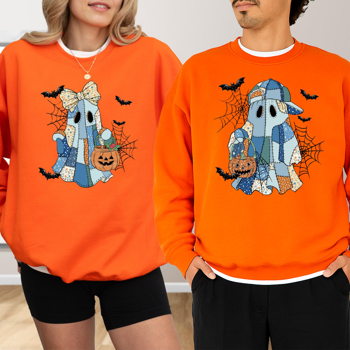 May include: Two bright orange crewneck sweatshirts featuring a graphic of a ghost made of blue patchwork fabric. One ghost wears a large bow, the other a baseball cap. Both ghosts hold a small orange jack-o'-lantern bucket amidst spiderwebs and bats.