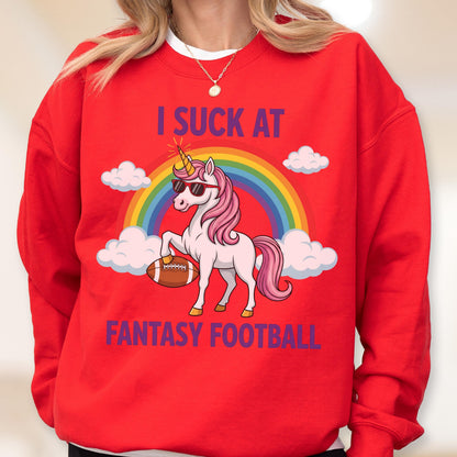 May include: A bright red crewneck sweatshirt featuring a graphic of a white unicorn with a pink mane, wearing sunglasses, holding a brown football, and standing in front of a rainbow and clouds, with the text I SUCK AT FANTASY FOOTBALL.
