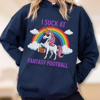 May include: A navy blue hooded sweatshirt featuring a graphic of a white unicorn with a pink mane, wearing sunglasses and holding a brown football. Above and below the unicorn, the text reads I SUCK AT FANTASY FOOTBALL in purple letters.