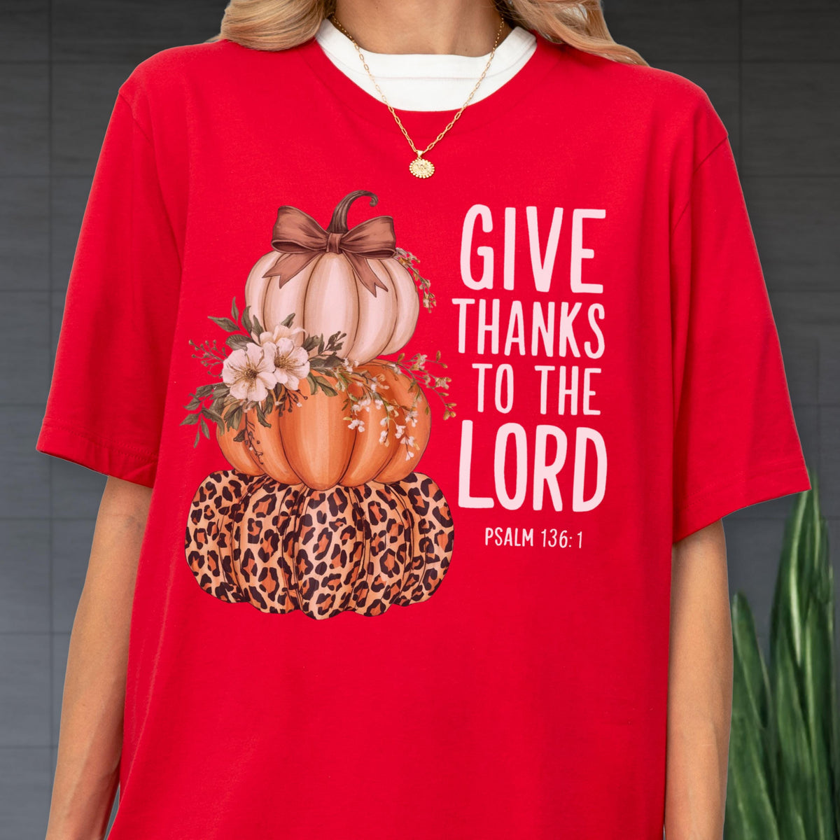 May include: Red t-shirt featuring a stacked pumpkin design with a leopard print base, an orange middle pumpkin, and a light pink top pumpkin. The shirt has the text "GIVE THANKS TO THE LORD" and "PSALM 136:1" in white.