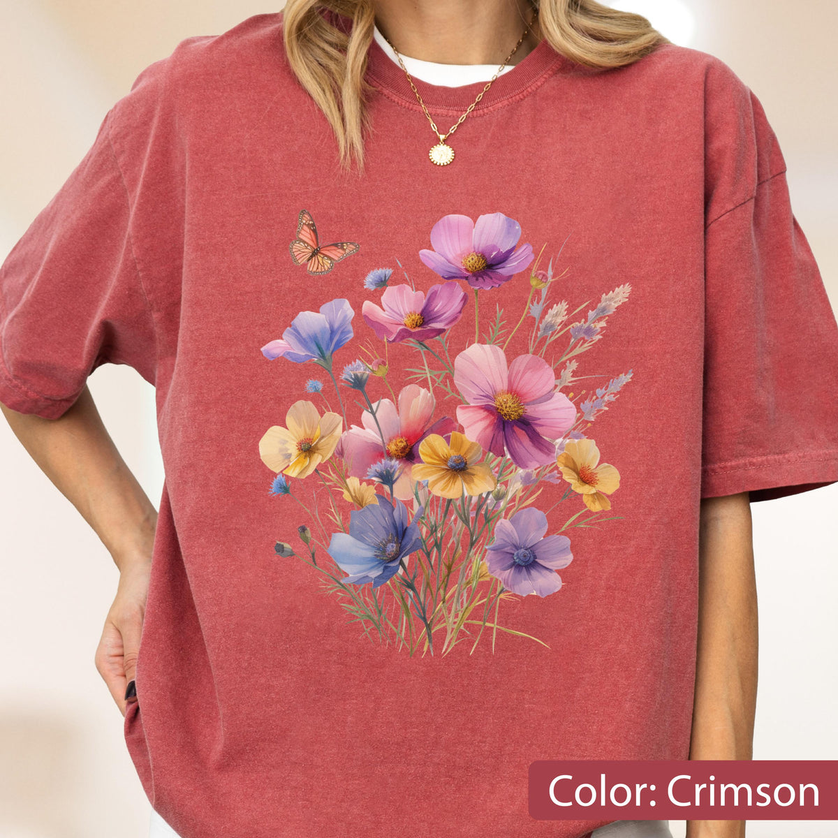 May include: A crimson short-sleeve t-shirt featuring a central graphic print of a colorful wildflower bouquet in shades of pink, purple, yellow, and blue, accompanied by a small orange butterfly hovering above the floral arrangement.