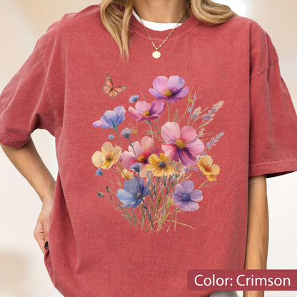 May include: A crimson short-sleeve t-shirt featuring a central graphic print of a colorful wildflower bouquet in shades of pink, purple, yellow, and blue, accompanied by a small orange butterfly hovering above the floral arrangement.