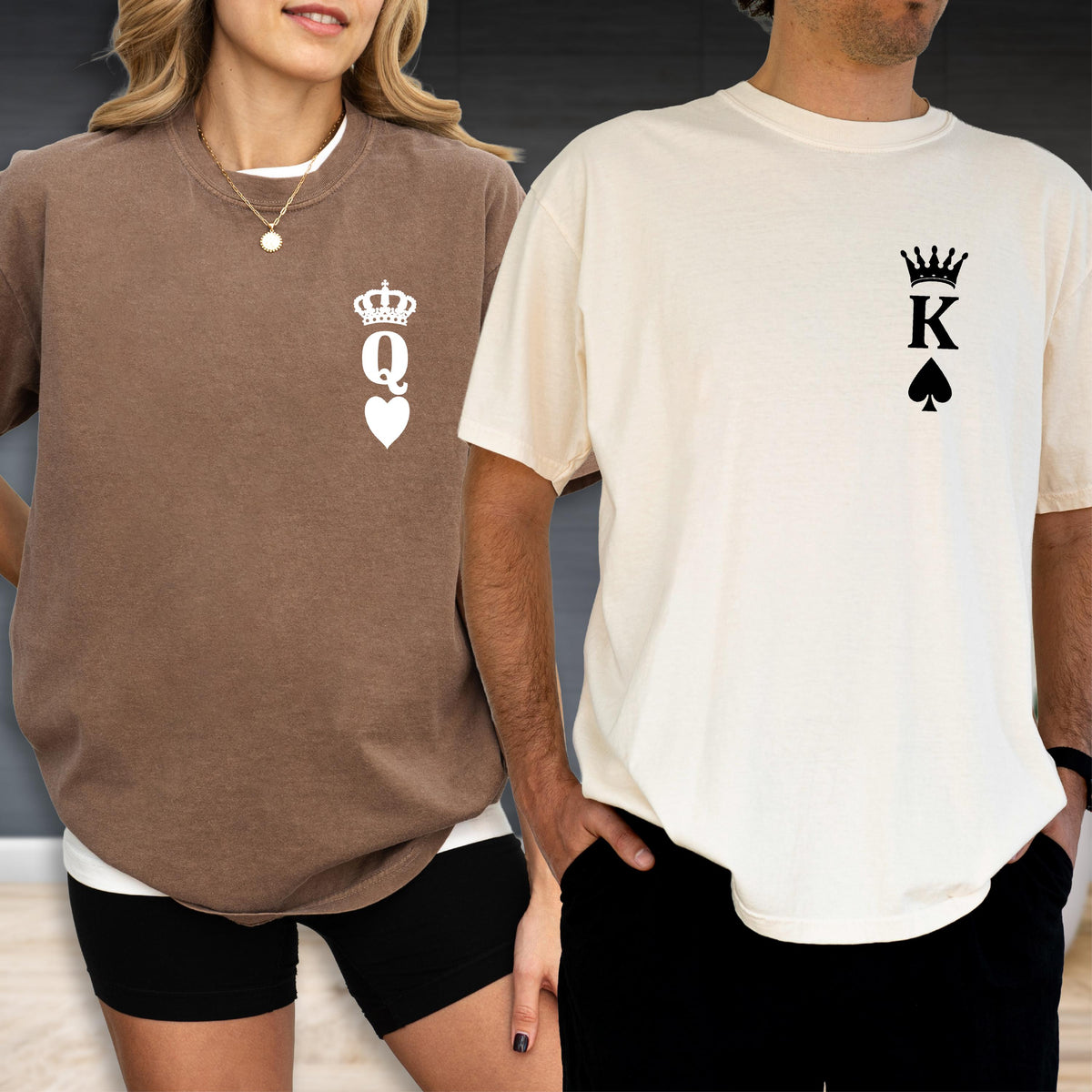 May include: A brown t-shirt featuring a white graphic of a crown above the letter Q and a heart symbol, and a cream t-shirt featuring a black graphic of a crown above the letter K and a spade symbol, both positioned on the left chest area.