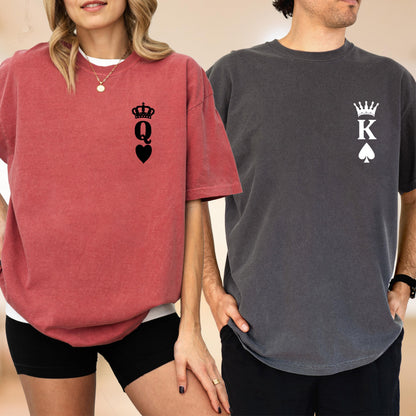 May include: A red t-shirt with a black graphic of a crown above the letter Q and a heart symbol on the chest, paired with a charcoal gray t-shirt featuring a white graphic of a crown above the letter K and a spade symbol on the chest.