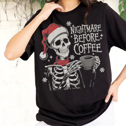 May include: Black t-shirt featuring a skeleton wearing a Santa hat and red scarf, holding a coffee cup. The text "NIGHTMARE BEFORE COFFEE" is printed above the skeleton. Snowflake graphics are also included in the design.