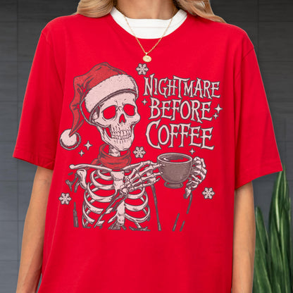 May include: Red t-shirt featuring a skeleton wearing a Santa hat and scarf, holding a coffee cup. The text "NIGHTMARE BEFORE COFFEE" is printed on the shirt, along with snowflake graphics. The shirt has a white collar.