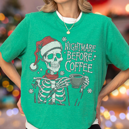 May include: Green t-shirt with a skeleton graphic wearing a Santa hat and scarf, holding a coffee cup. The text "Nightmare Before Coffee" is printed on the shirt. The design has a festive, yet spooky theme.