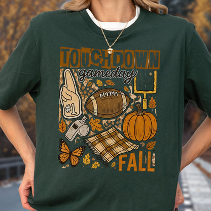 May include: Dark green t-shirt with a fall-themed graphic. The design includes a football, pumpkin, leaves, and the words "TOUCHDOWN gameday FALL!" A foam finger and a whistle are also featured.