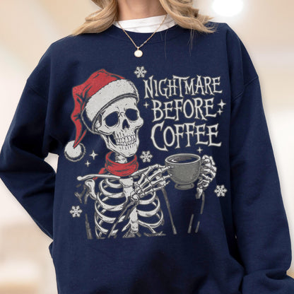 May include: Navy blue sweatshirt featuring a skeleton wearing a Santa hat and red scarf, holding a coffee cup. The text "NIGHTMARE BEFORE COFFEE" is printed on the front, with snowflake accents. A festive and spooky design.