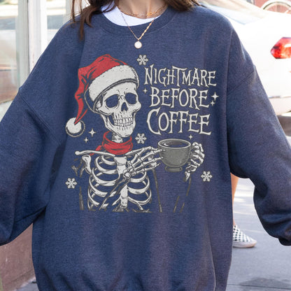 May include: Navy blue sweatshirt with a graphic of a skeleton wearing a Santa hat and scarf, holding a coffee cup. The text "NIGHTMARE BEFORE COFFEE" is printed on the front, with snowflake accents.